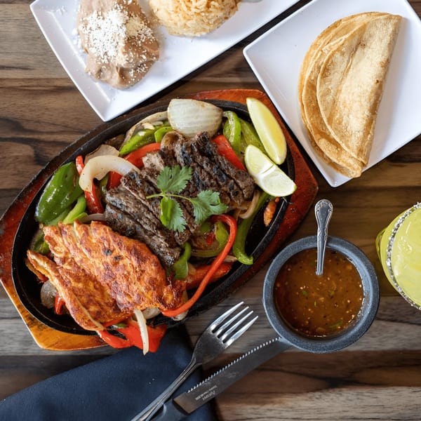 Don Jose Mexican Restaurant's sizzling fajitas with steak, chicken, peppers, onions, and limes, served with sides.