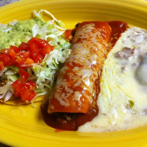Don Jose's Mexican enchilada with red sauce and melted cheese, served with refried beans, guacamole, and salad.