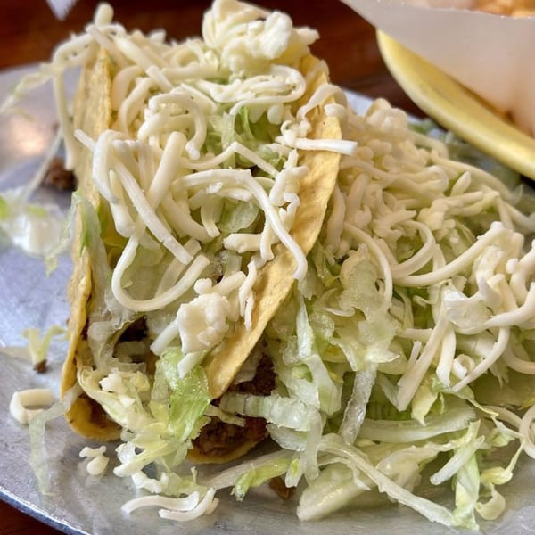 Two crispy tacos from Don Jose Mexican Restaurant, generously filled with seasoned meat, shredded lettuce, and cheese.