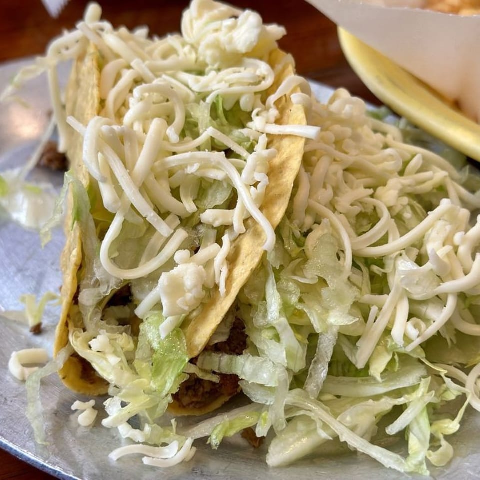 Two crispy tacos from Don Jose Mexican Restaurant, generously filled with seasoned meat, shredded lettuce, and cheese.