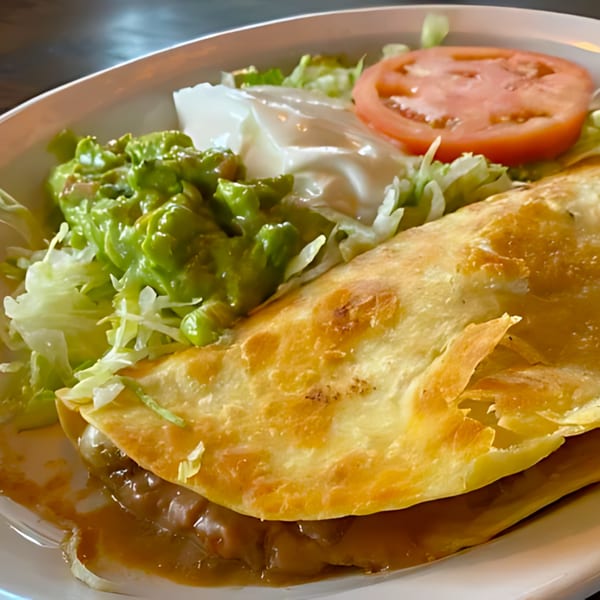 Don Jose Mexican Restaurant's quesadilla with guacamole, sour cream, lettuce, and tomato on a white plate.